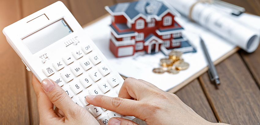 A female hand operating a calculator in front of a Villa house model